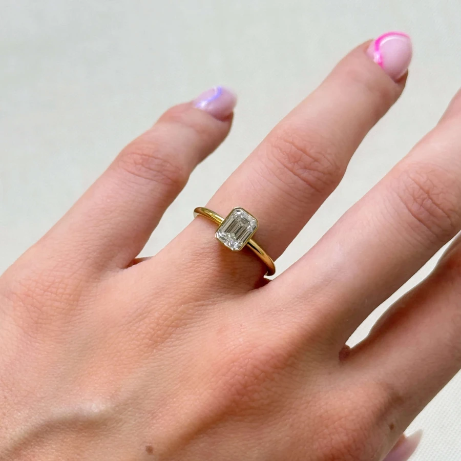 pierscionek-zareczynowy-bezel-moissanit-1ct-szlif-szmaragdowy-na-dloni-zolte-zloto-stellar-hariets.jpg